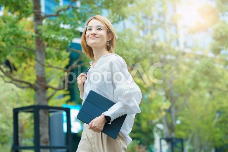 緑あふれるオフィス街を歩く女性  女性,フリーランス,自由の写真素材