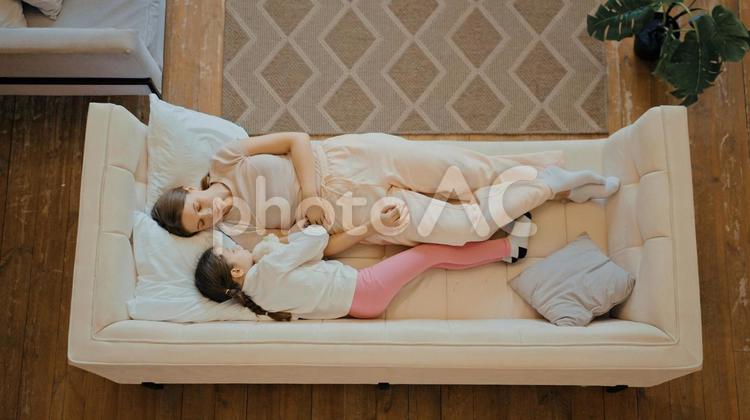 ソファーで向かい合って横になる親子 親子,女性,女の子の写真素材