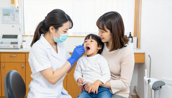 母に抱かれて歯医者さんから診察される子 母に抱かれて歯医者さんから診察される子の写真