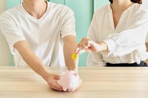 貯金箱にお金を入れる男女 貯金箱にお金を入れる男女 貯金,貯蓄,貯めるの写真素材