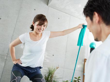 Japanese woman receiving tube training instruction from a personal trainer Japanese woman receiving tube training instruction from a personal trainer