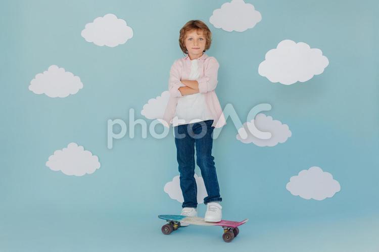 腕組みをしてスケボーに乗る男の子 男の子,スケートボード,乗り物の写真素材