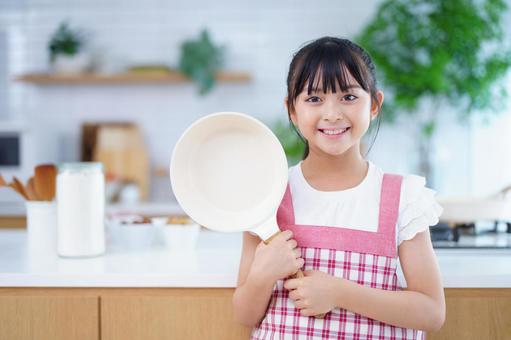 キッチンで料理の準備をする明るい少女 女の子,フライパン,持つの写真素材