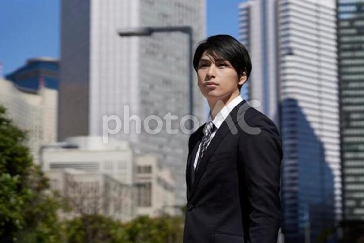 オフィス街で真剣な表情で立つビジネスマン ビジネスマン,男性,真剣の写真素材