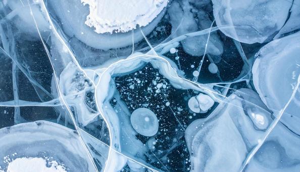 冬の湖面に張ったひび割れ氷と雪の模様 冬の湖面に張ったひび割れ氷と雪の模様の写真
