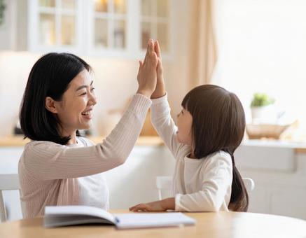 家庭でハイタッチするお母さんと子供 家庭でハイタッチするお母さんと子供の写真