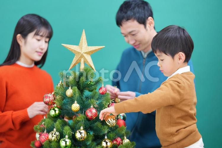 家族でオーナメントをクリスマスツリーに飾り付けているところ 家族,人物,男性の写真素材