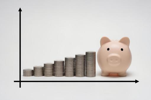 積みあがるコインと豚の貯金箱とグラフ 積みあがるコインと豚の貯金箱とグラフの写真