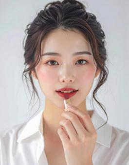 リップを塗る若い女性の美容ポートレートの写真