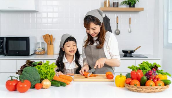 キッチンで料理をする母親と女の子 キッチンで料理をする母親と女の子の写真