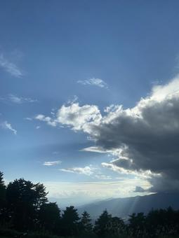 雲間から光が差し込む青空と森の風景 雲間から光が差し込む青空と森の風景の写真