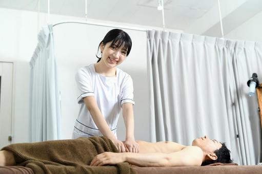 笑顔で男性患者に施術する女性セラピスト 痩身エステ,エステ,痩身の写真素材