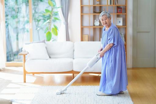 微笑み掃除中の青いワンピースの女性 女性,掃除,掃除機の写真素材