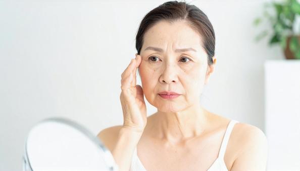 ほうれい線を気にしてほほを触る中年の女性 ほうれい線を気にしてほほを触る中年の女性の写真