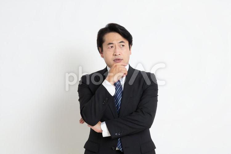 アゴに手をあて悩んでいる中年のサラリーマン男性 中年,上司,会社員の写真素材