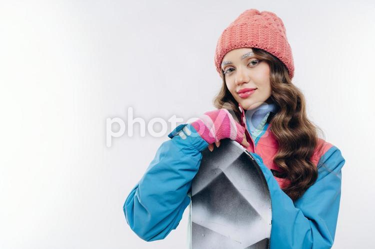スノーボードを抱えているカメラ目線の女性 冬,スポーツ,ウィンタースポーツの写真素材