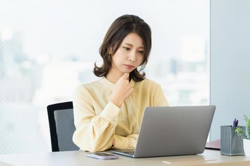 パソコンを使いながら考える女性 パソコンを使いながら考える女性 女性,パソコン,考えるの写真素材