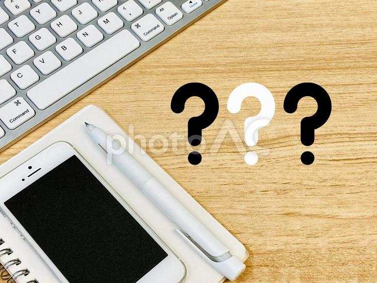 机の上のPCとスマホ＋はてなマーク 疑問,質問,クエスチョンの写真素材