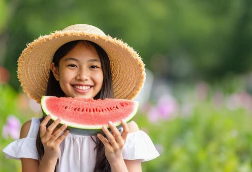 麦わら帽子の女の子がスイカを持っているの写真