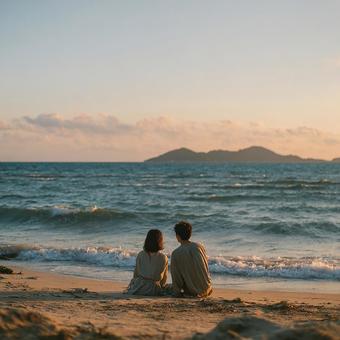 ビーチに座って海を眺める若者カップルの写真