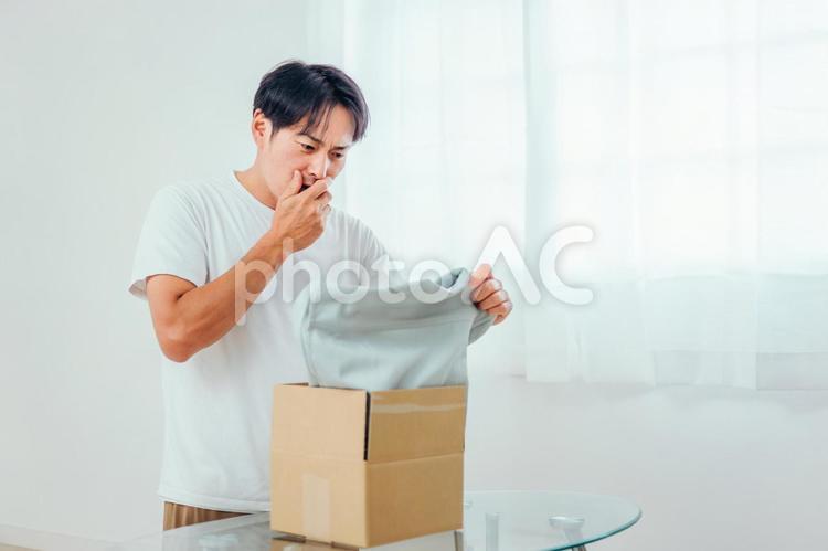 届いた商品に驚く男性（不良品・返品） 不良品,返品,クーリングオフの写真素材