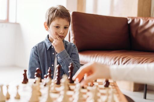 ソファテーブルでチェスをしている男の子とお父さんの手 ソファテーブルでチェスをしている男の子とお父さんの手の写真
