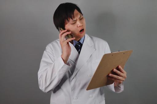 電話で話す医師の困惑表情 電話で話す医師の困惑表情 医師,男性,白衣の写真素材