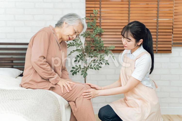痛がる高齢者女性と介護士（膝痛） 膝,高齢者,ヒザの写真素材