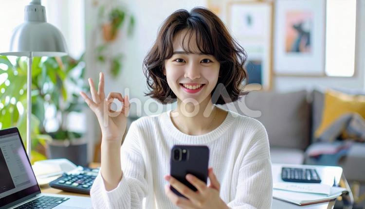 家計がうまくいきスマホ片手に微笑む女性 パソコン,家計簿,節約の写真素材
