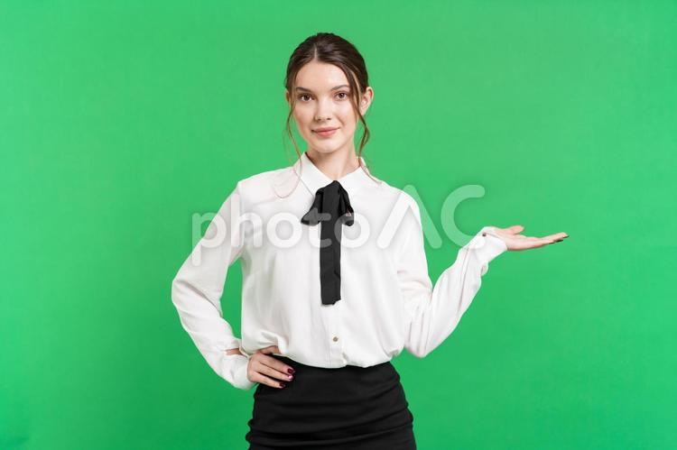 腰に手を当て微笑みポーズする女性（緑背景） 女性,微笑む,紹介の写真素材