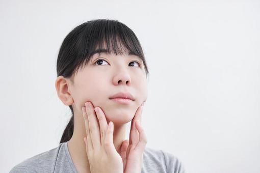 Japanese female junior high school student massaging the chin, cara pequeña, masaje, chica, JPG