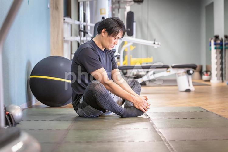 スポーツジムでストレッチする男性（笑顔） ストレッチ,柔軟運動,柔軟体操の写真素材
