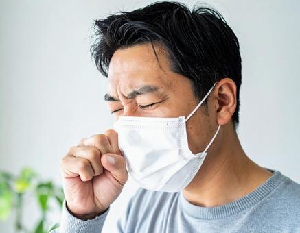 マスクを着用して咳をするの男性 マスクを着用して咳をするの男性の写真