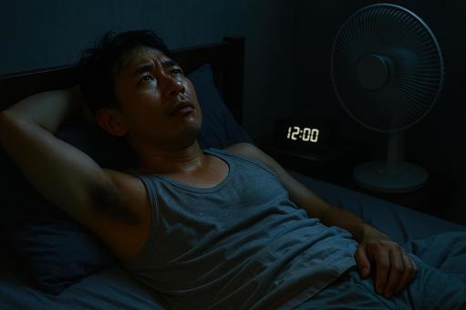 熱帯夜に寝苦しそうな男性 熱帯夜に寝苦しそうな男性の写真