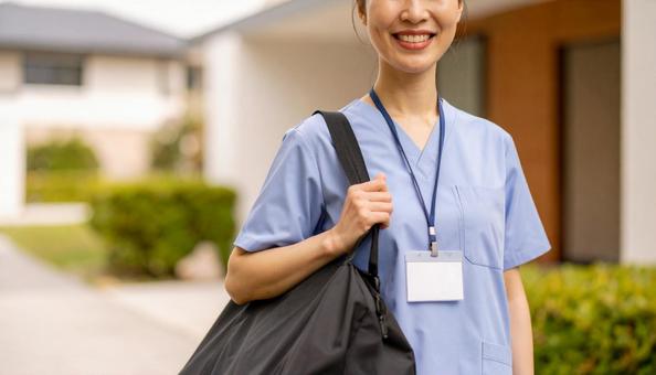 訪問看護で訪問先の住宅に笑顔で立つ女性の写真