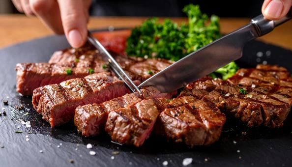鉄板焼きのステーキをナイフで切る 鉄板焼きのステーキをナイフで切るの写真