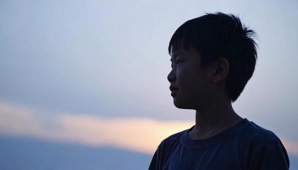 夕焼けの空を見つめる日本人の少年 夕焼けの空を見つめる日本人の少年の写真