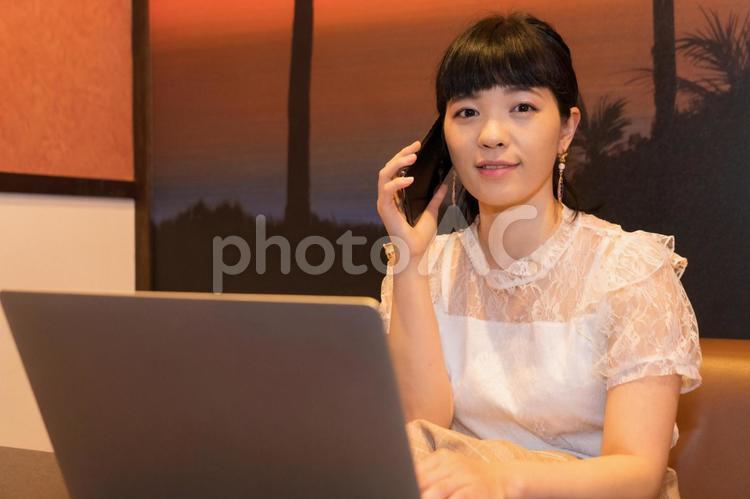 ノートパソコンと電話する女性 ノートパソコンと電話する女性 在宅ワーク,スマホ,通話の写真素材