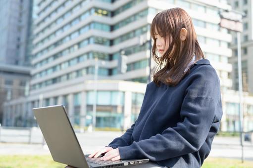 ベンチに座ってパソコンを操作する女子高生 高校生,女子高生,女性の写真素材