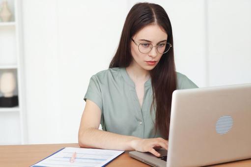 ノートPCで仕事をする眼鏡をかけた女性スタッフ 保険業,事務職,接客業の写真素材