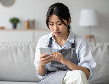 スマホを見て悩む女性 スマホを見て悩む女性の写真
