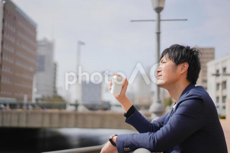 野外でコーヒーを飲む男性 ビジネス,考える,悩むの写真素材