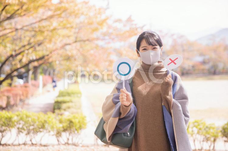 秋の公園でマスクをつけてマルを作る女性 マスク,コロナ対策,感染対策の写真素材