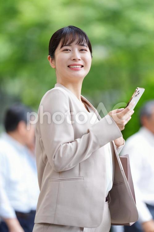 振り向いて携帯を持って微笑む女性 女性,人物,大学生の写真素材