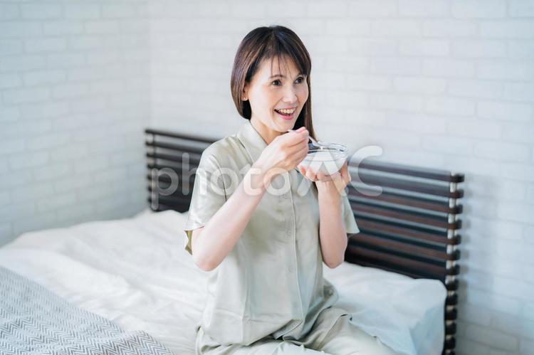 寝室でヨーグルトを食べる女性（笑顔） ヨーグルト,乳酸菌,菌活の写真素材
