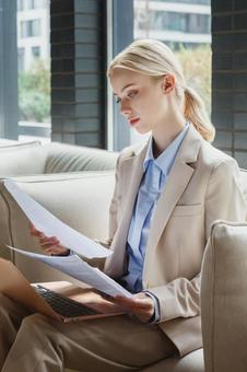 オフィスのソファで資料を見ている女性 ビジネスウーマン,ビジネス,女性の写真素材