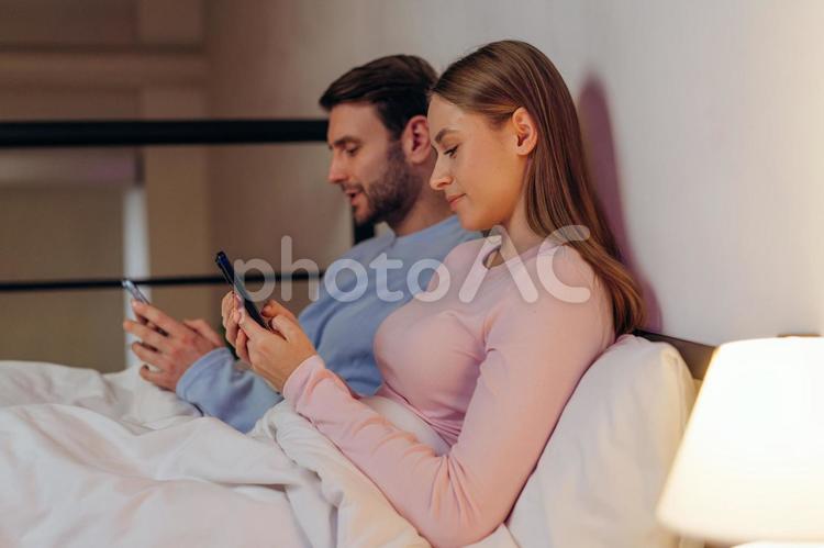 携帯を見るカップルの横顔 男性,女性,もたれるの写真素材
