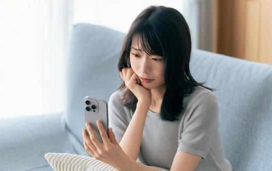 スマホを見て困った顔で考える女性 スマホを見て困った顔で考える女性 女性,スマホ,スマートフォンの写真素材