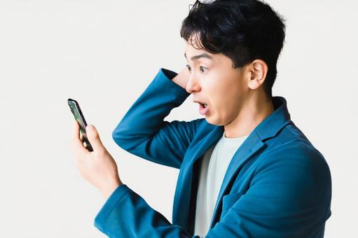 スマホを見て驚く男性ビジネスマン スマホを見て驚く男性ビジネスマン 男性,スマホ,スマートフォンの写真素材