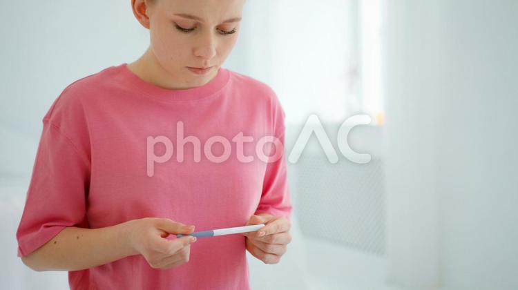 真剣な顔で検査薬を見る女性 女性,妊娠検査薬,持つの写真素材